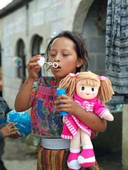 Guatemala - Meisje blij met pop en bellenblaas